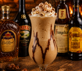 A kodiak sled dog cocktail recipe served in a hurricane glass with whipped cream, hazelnuts, and chocolate drizzle in a rustic log cabin bar.