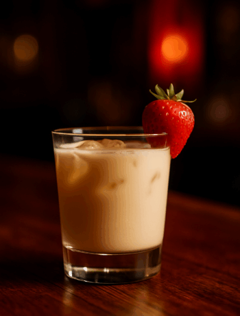 Multiple Orgasm cocktail recipe in an old fashioned glass with a strawberry garnish on a wooden bar