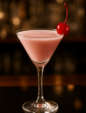 A creamy pink tutu cocktail recipe served in a chilled cocktail glass with a cherry garnish.