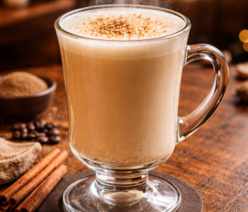 An irish cow cocktail recipe served warm in an Irish coffee mug topped with nutmeg on a wooden table.